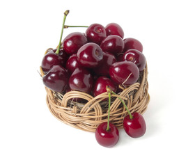 Ripe cherry in a wicker basket. Isolated on white background
