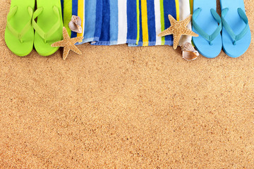 Fototapeta na wymiar Beach top border with flip flops in a row line tropical background sand striped blue towel couple sunbathing summer holiday vacation photo