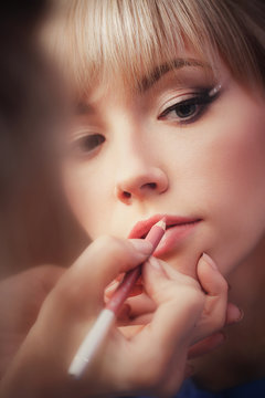 Young beautiful girl applying make-up by make-up artist close up