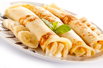 Crepes with bananas and cream on white background 