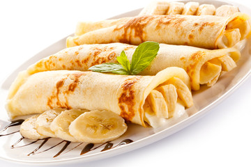 Crepes with bananas and cream on white background 