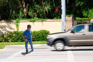 A man is jaywalking across an intersection when the signal is clearly showing the do not cross symbol.  - 85969090