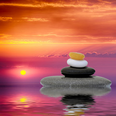 Zen spa concept background - Zen massage stones at sunset reflected in water