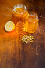 honey in a glass with label on a wooden table with chamomile tea and lemon
