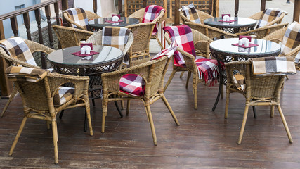 chairs with colorful rugs and tables on the terrace of a street
