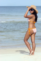 Fototapeta na wymiar Attractive woman in bikini posing with cowboy hat on the sea beach