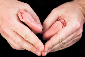 Fototapeta premium Newborn baby feet in father hands