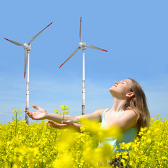  woman on rapeseed field in the background wind turbines