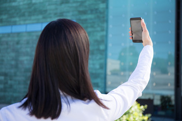 back view of business woman making selfie photo on smartphone