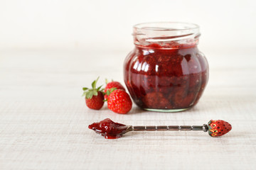 Strawberry jam in a jar on wooden background