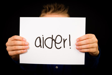 Child holding sign with French word Aider - Help