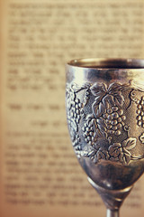 vintage shabbath silver cup of wine in front of torah book