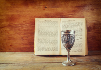 vintage shabbath silver cup of wine in front of torah book