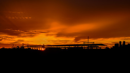 silhouette, sunrise over factory, process color.