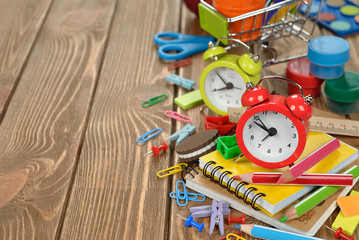 Red alarm clock and colorful school supplies