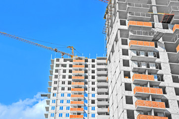 Crane and building construction site against blue sky