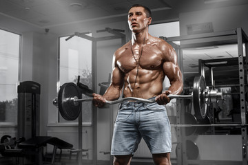 Fototapeta na wymiar Muscular man working out in gym doing exercises with barbell, strong male naked torso abs