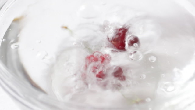 Cherries are strewed in a vase with water (slow motion)
