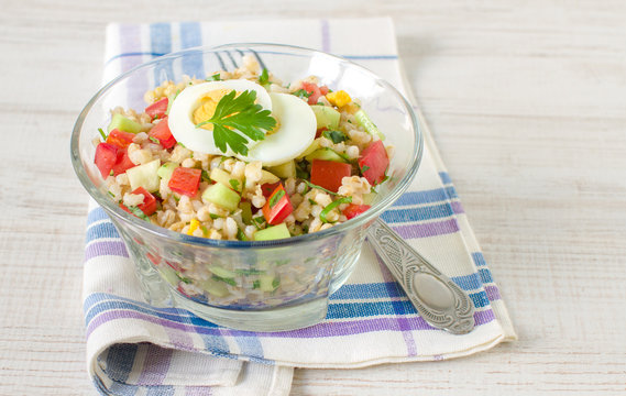 Warm salad with red and yellow pepper, barley, cucumber, tomato and egg