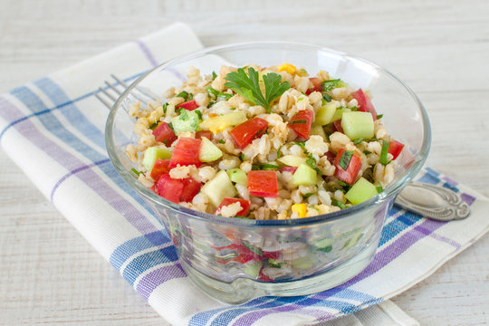 Warm salad with red and yellow pepper, barley, cucumber, tomato