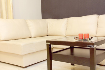 Interior with coffee table and white corner leather sofa .