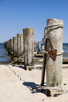 Alter Holzsteg mit einem rostigen Anker im Vordergrund