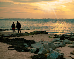 Sunset on rocky beach with two silhouetted people