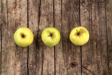 Three green apples on a wooden background