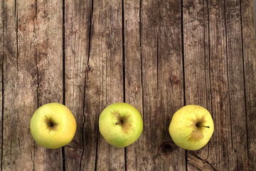 Three green apples on a wooden background