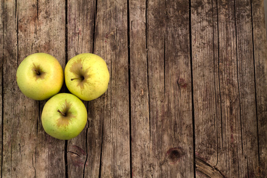 Three green apples on a wooden background