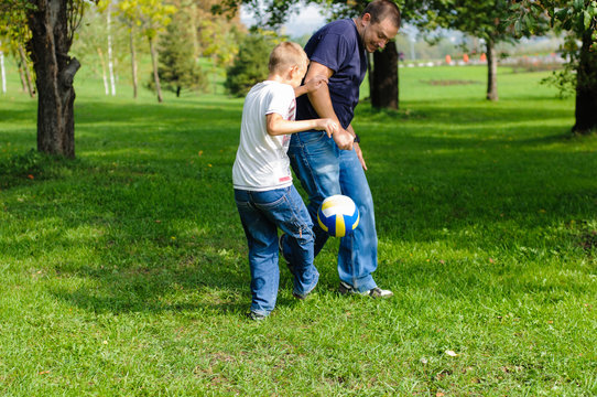 Young boy playing football with his father