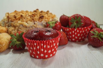 muffin and fresh strawberries, croissants , cake with almonds
