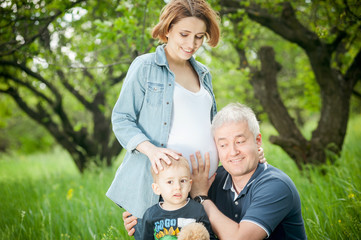 Fototapeta premium Happy family. Father and son listening pregnant mother's belly.