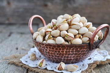 Pistachio  in a copper plate on a wooden table