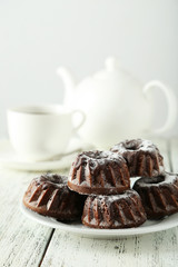 Chocolate bundt cakes on plate on white wooden background