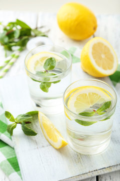 Fresh lemonade with lemon on white wooden background