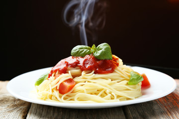 Spaghetti with tomatoes and basil on plate on grey wooden 