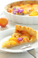Slice of apricot pie on white wooden background
