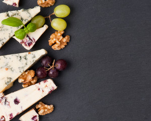 Different types of cheeses on black board.