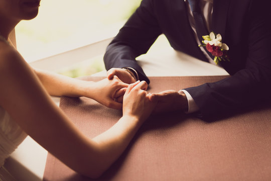 toned photo of bride and groom holding hands at restaurant