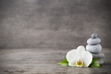 Obraz na płótnie Canvas White orchid and spa stones on the grey background.