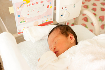 ベビーベッドで眠る新生児