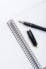 A spiral notebook with black ball pen over the white background, isolated