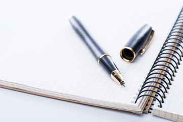 A spiral notebook with black ball pen over the white background, isolated
