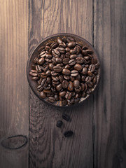 Coffee beans in a ceramic plate on the wooden table. Retro colors  tone.