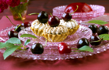 Cakes (cupcakes) with dark cherries on glass plate