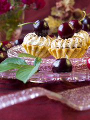 Cakes (cupcakes) with dark cherries on glass plate