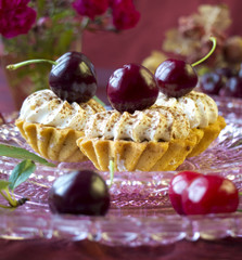 Cakes (cupcakes) with dark cherries on glass plate
