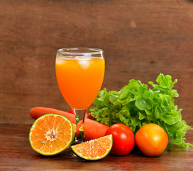 Fresh orange juices and vegetable on wooden table