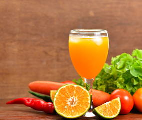Fresh orange juices and vegetable on wooden table